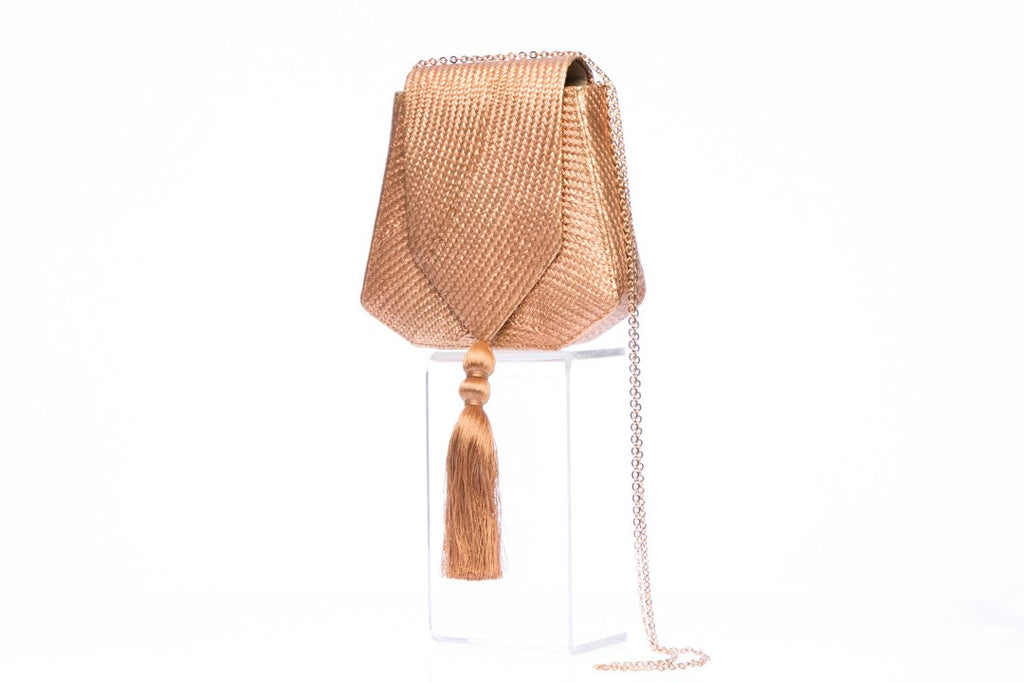 Bronze Glory Shoulder Bag, a handwoven clutch made from 100% natural plant fibers, showcasing sustainable luxury and elegance. This eye-catching bag features a lustrous bronze finish, a gold tassel for added flair, and a brass drop-in chain strap for versatile carrying. Perfect for garden weddings and fancy dinners, the fully lined interior is designed to organize essentials like mobile phones, credit cards, and lipstick.