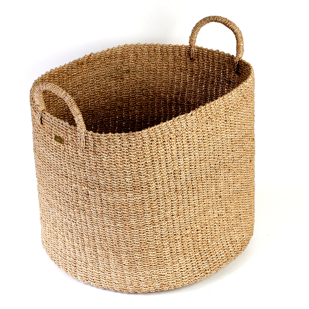 Camille Round Basket Hamper made from 100% natural plant fiber, featuring a beautifully woven design that adds rustic charm and eco-friendly storage to any room. Ideal for organizing laundry, toys, throw pillows, and bath essentials, while also enhancing home decor with indoor plants. Care instructions recommend avoiding prolonged water exposure and using spot cleaning for maintenance.