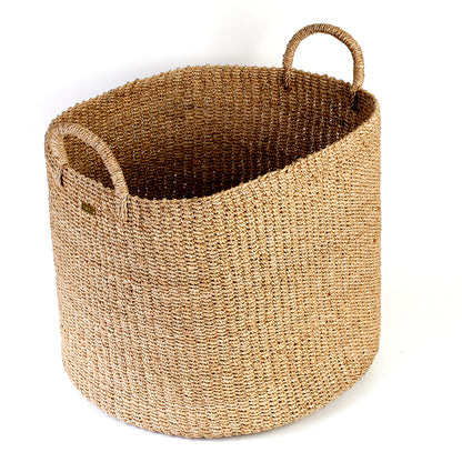 Camille Round Basket Hamper made from 100% natural plant fiber, featuring a beautifully woven design that adds rustic charm and eco-friendly storage to any room. Ideal for organizing laundry, toys, throw pillows, and bath essentials, while also enhancing home decor with indoor plants. Care instructions recommend avoiding prolonged water exposure and using spot cleaning for maintenance.